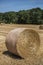 Close-up of a round haystack in the foreground with other ones dispersed in a field in the French countryside