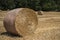 Close-up of a round haystack in the foreground with other ones dispersed in a field in the French countryside