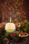 Close up round ivory burning Christmas candle on advent wreath with natural decor on the old rustic table with blurred luminous ba