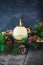 Close up round ivory burning Christmas candle on advent wreath with natural decor on the old rustic table with dark stone backgrou