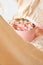 Close up of round pink box with ribbon,flowers,french macarons inside covered by beige texture with open top