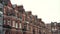 Close-up of Row of typical English terraced brick houses against the grey sky in autumn day. Action. Traditional English