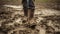 Close up of rubber boots in muddy field. Farmer inspects property after heavy rain and flooding