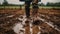 Close up of rubber boots in muddy field. Farmer inspects property after heavy rain and flooding