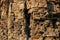 Close-up rufous stony wall with layered uneven hollowed-out surface.