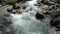 Close-up of the rushing, bubbling and foaming cold water of a mountain stream in the Alps