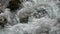 Close-up of the rushing, bubbling and foaming cold water of a mountain stream in the Alps