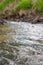 Close-up of rushing water, photo of wave texture and background. Waves of a small stream.