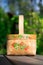 Close-up russian domestic birch bast basket with Khokhloma traditional painting on it on green trees background