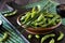 Close up of a rustic bowl of edamame beans in the shell with chopsticks on top.