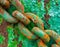 Close-up of a rusty and weathered metal chain with green paint, highlighting texture contrast