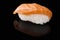 Close-up of Sake sushi with salmon on a black background with reflection.