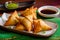 Close-up of samosas with a side of tamarind sauce on a vibrant green plate, ready to be savored