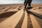 close-up of sandboarder riding down dune, with view of endless desert wilderness in the background
