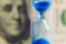 A close-up of the sandglass and the dollar background.