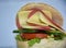 Close up of a sandwich with  cheddar, salami, lettuce, cucumber, tomatoes