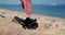 Close-up of a sandy beach near the ocean where a drone falls from the sky.