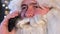 Close up of Santa Claus talking on smartphone. Young Santa Claus uses a gadget