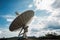 close-up of satellite dish, with the blue sky and clouds visible in the background