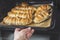 Close up sausages in the dough on a baking sheet. Baking on parchment with woman`s hand