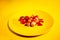 Close up of sausages in sauce with cherry tomatoes on yellow plate. Appetizing frankfurters with small red tomatoes and