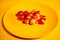 Close up of sausages in sauce with cherry tomatoes on yellow plate. Appetizing frankfurters with small red tomatoes and