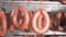 Close up of sausages tied up to a metal crossbar in a factory unit