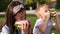 Close-up of school children biting fresh sandwiches in the park on the grass.