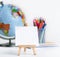 Close up of school easel, world globe and pencils on white