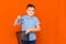 Close up schoolboy in a blue t-shirt throws glasses in the bin on a orange background