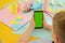 a close-up of a schoolboy who holds a mobile in his hands mobile phone with green screen. Easter crafts, craft tools and