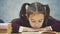 Close up a schoolgirl girl sits on a gray background. During this time he carefully reads the book. Diligent student