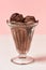 Close up of scoops of tasty chocolate ice cream in a glass sundae dish isolated over light background