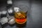 Close up of Scotch whiskey or Grain scotch in a transparent glass with ice cubes on black colored wooden surface.