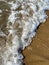 Close-up of the sea coast, clear sea water with shallow waves and a narrow strip of white foam with bubbles washes the