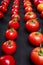 Close-up of seasonal tomatoes organized in lines on a black background. Ketchup ingredients.
