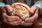 A close-up of seasoned hands tenderly holding a loaf of freshly baked bread, illustrating the dedication and passion of