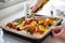 Close Up Of Seasoning Tray Of Vegetables For Roasting With Olive Oil Ready For Vegan Meal