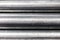 Close up of section of steel pipes stacked on top of each other/textured metallic background