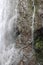 Close up of a section of Wailua Falls running down volcanic rock which is covered with moss in Hana, Maui