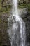 Close up of a section of Wailua Falls tumbling over a volcanic rock cliffside in Hana, Maui, Hawaii