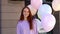 Close-up of seductive smiling girl with red hair greeting, looks at camera and holding of balloons.