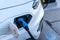 Close up selective focus of blue plug charging a white electric car