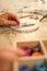 Close up in selective focus of female hands making a macramÃ© bracelet with kumihimo on a wooden table with tools, spools of