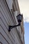 Close up, selective focus of old-style black street lamp lantern hanging on the renewed striped building wall. Blue sky