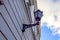 Close up, selective focus of old-style black street lamp lantern on the renewed striped building wall. Blue sky with