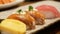 close up selective focus to a plate of japanese food with sushi while hand using chopstick to pick up a sushi from a plate in