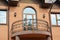 A close-up on semi-circled balcony with wrought iron railings, arched glass door