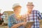 Close up of senior farmer using digital tablet with mature farmer standing against tractor in field