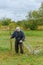 Close up of senior farmer using scythe to mow the lawn traditionally